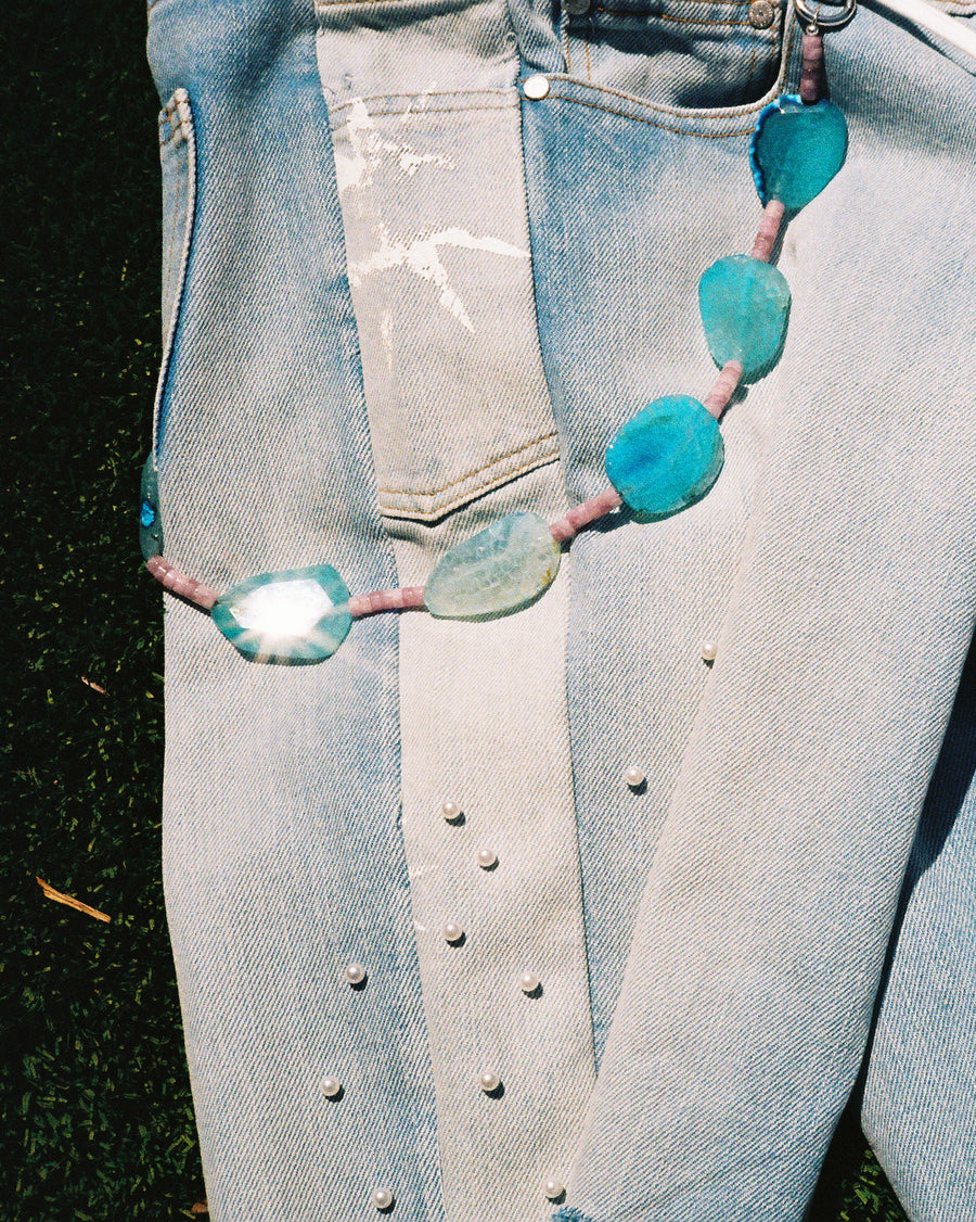 The Gemstone Wallet Chain hanging from the belt loop of light wash jeans, sun coming through the blue agate