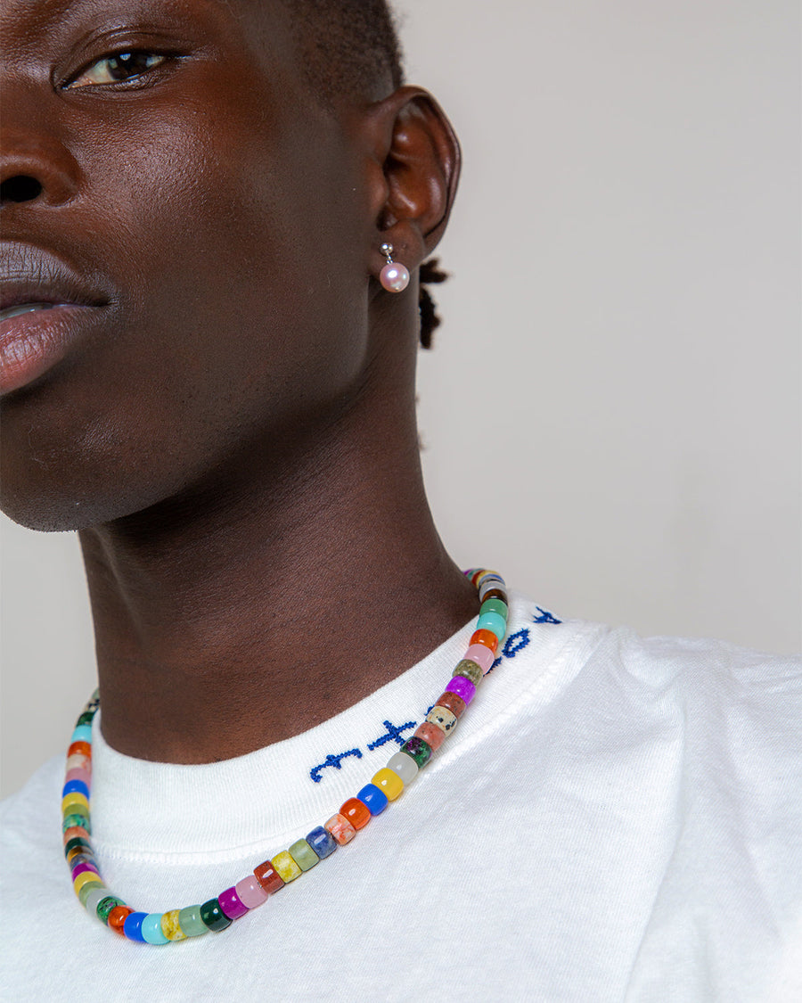The Protection Necklace worn at the collar over a white T-shirt, its gemstone beads each a different color