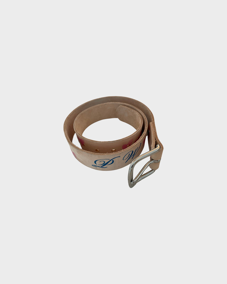 The Airbrush Belt coiled, showing the PW lettering painted in blue script and the silver buckle