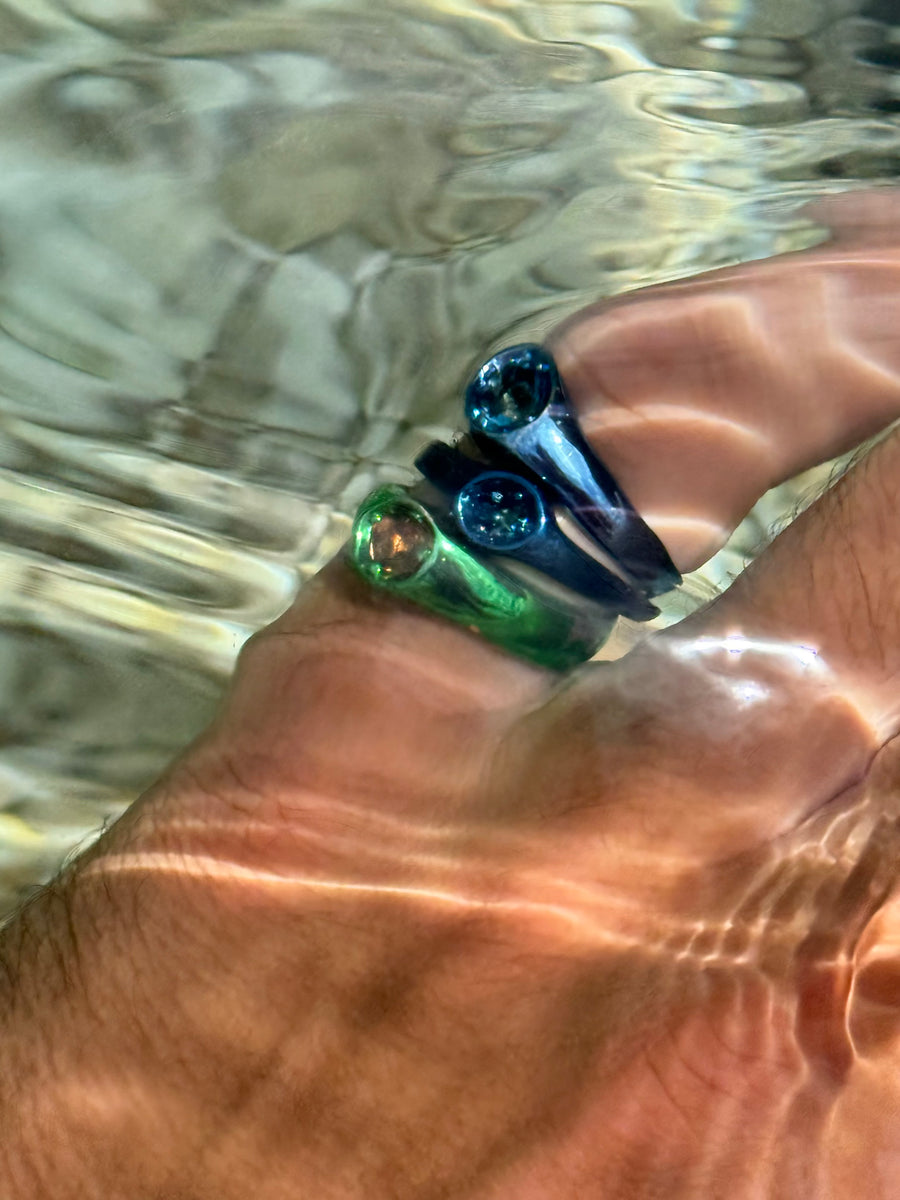 Blue and green Polite solitaire rings worn together, under water