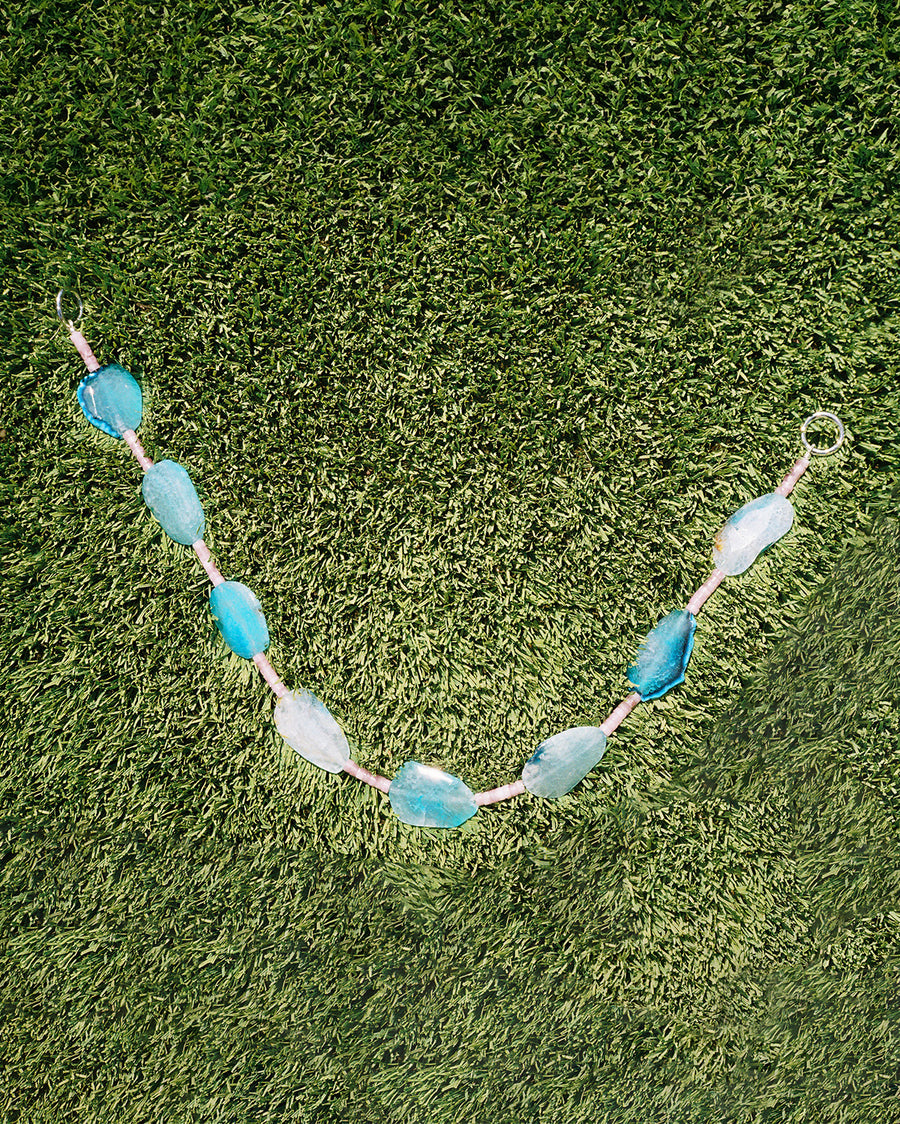 The Gemstone Wallet Chain laid out on grass, each slice of blue agate a different shade