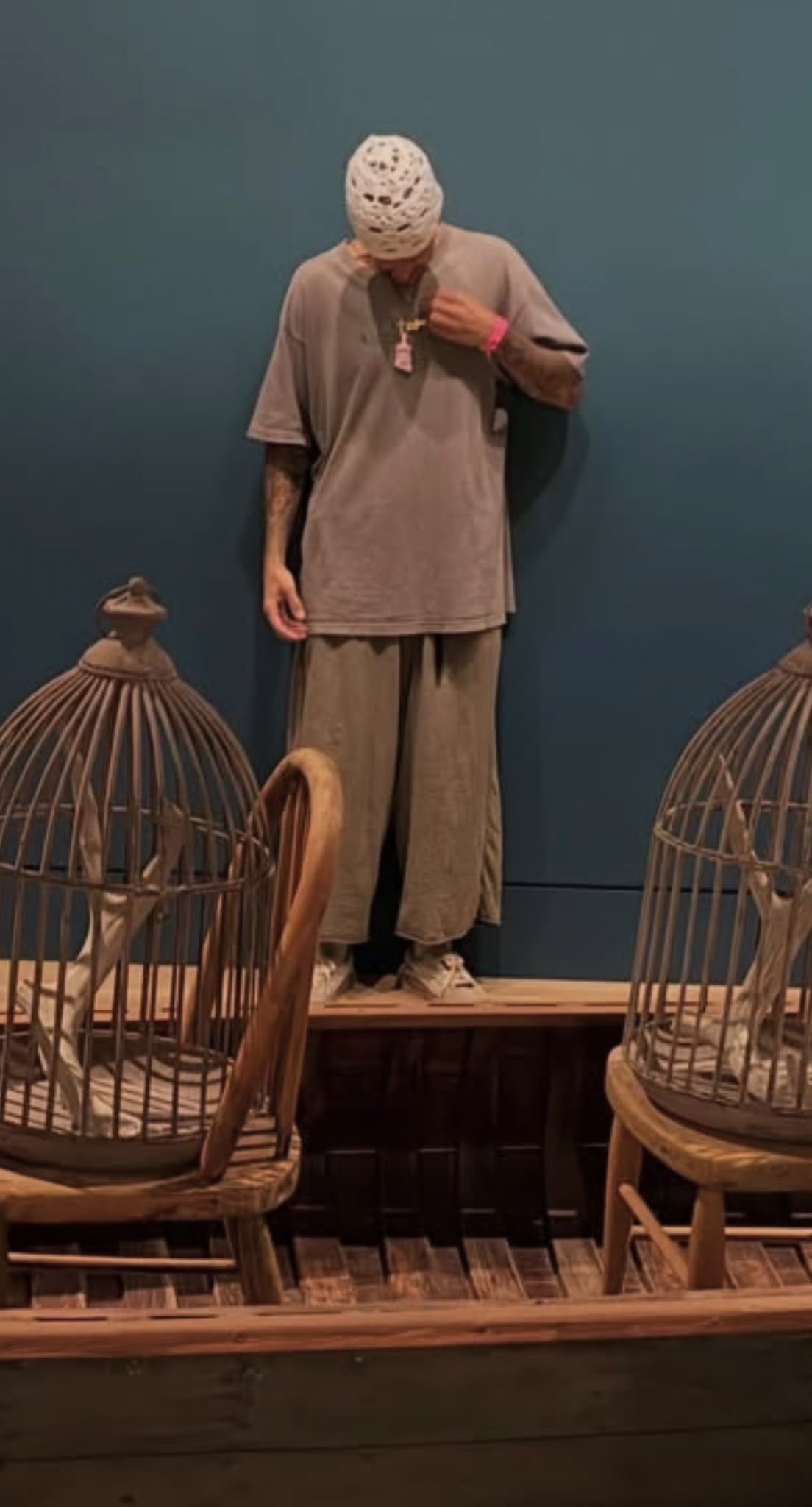 Justin Bieber standing against a blue wall wearing the pink Jesus Peace